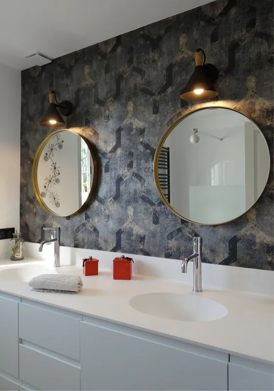 Deux miroirs ronds au-dessus d’une double vasque, éclairés par deux appliques murales.